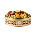 Colorful dried fruit mix in a decorative gold container on a white background