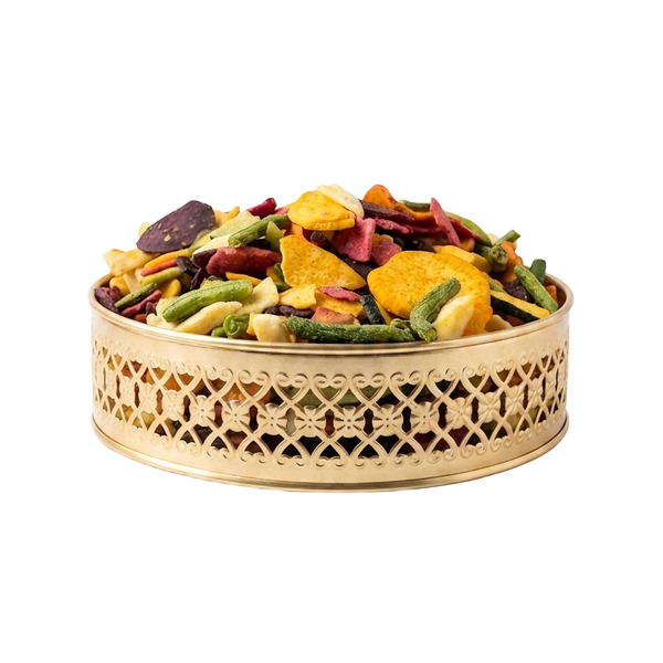 Colorful dried fruit mix in a decorative gold container on a white background