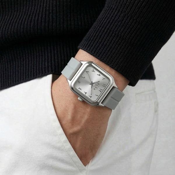 Person wearing a silver watch with a black strap on a plain background