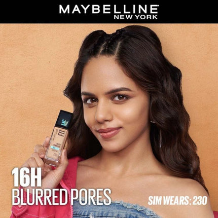 Woman holding a Maybelline foundation bottle with text '16H Blurred Pores' on a beige background