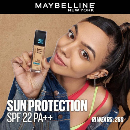 Woman holding a Maybelline Fit Me foundation bottle with text about sun protection and product details.