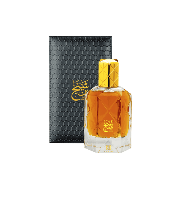 Perfume bottle with gold cap and black hexagonal packaging on a white background