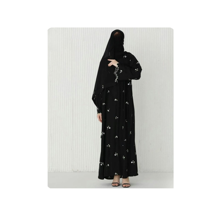 Person wearing a black abaya with floral embroidery on a white background