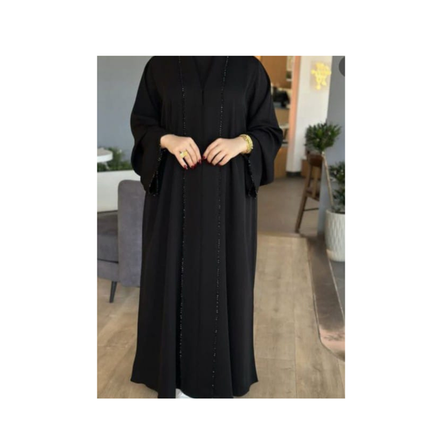 Person wearing a black abaya in a room with furniture and decor.