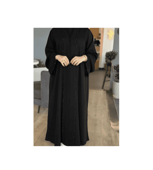 Person wearing a black abaya in a room with furniture and decor.