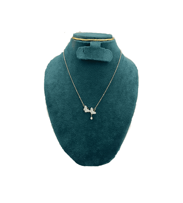 Gold necklace with a pendant on a green velvet bust against a white background