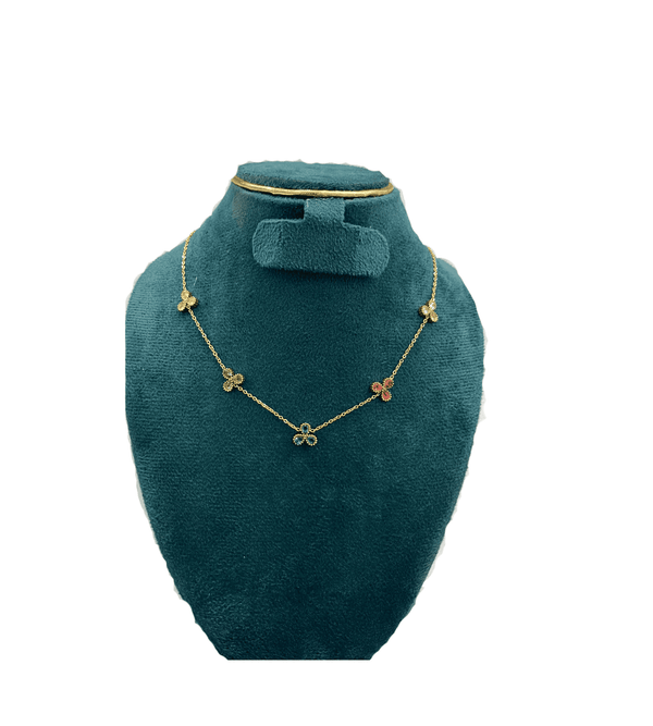 Gold necklace with clover pendants on a green velvet stand against a white background