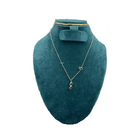 Gold necklace on a teal mannequin bust with a white background