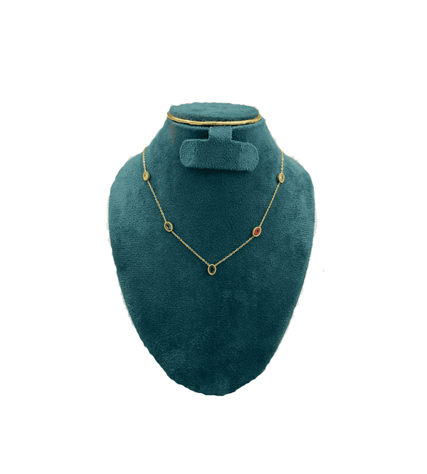 Teal velvet jewelry display with gold necklace and earrings on a white background
