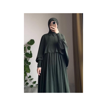 Person wearing a dark green outfit with a matching hijab in front of a mirror.