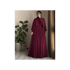 Person wearing a burgundy dress standing in front of a plant.