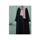 Person wearing a black outfit with a pink hijab against a green door background