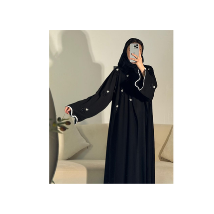 Person wearing a black abaya with white details in a neutral setting