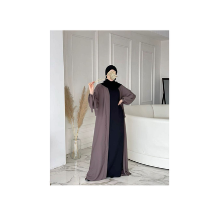 Woman wearing a two-tone dress with a black and brown gradient in a minimalistic room.