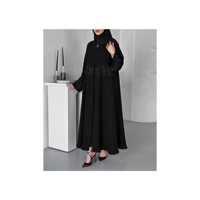 Person wearing a black dress with lace details in an indoor setting.