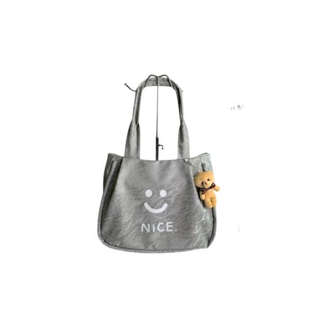 Gray tote bag with a smiley face and 'NICE' text, containing a small teddy bear, on a white background.