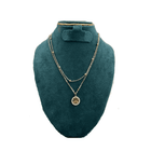 Gold necklace with a pendant on a green velvet bust against a white background