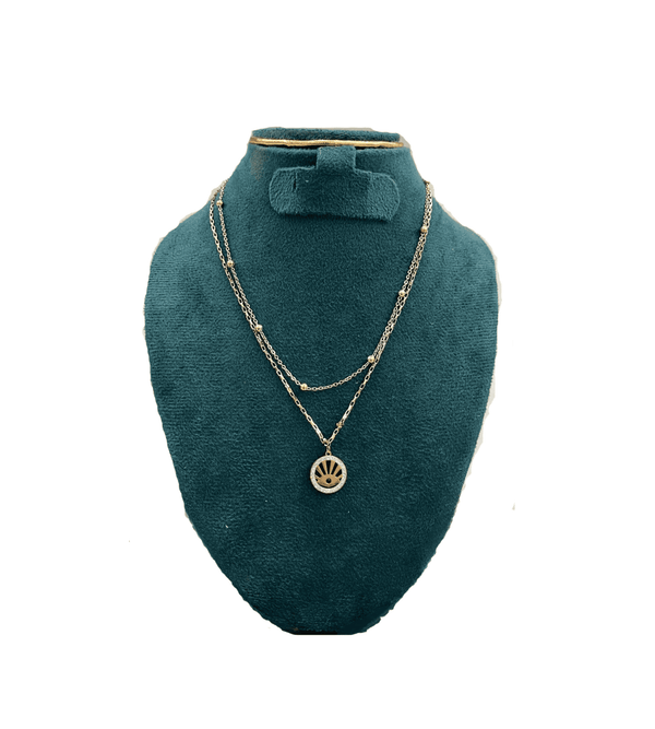 Gold necklace with a pendant on a green velvet bust against a white background