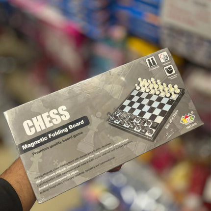 Chess magnetic folding board game packaging held by a person with a blurred store background