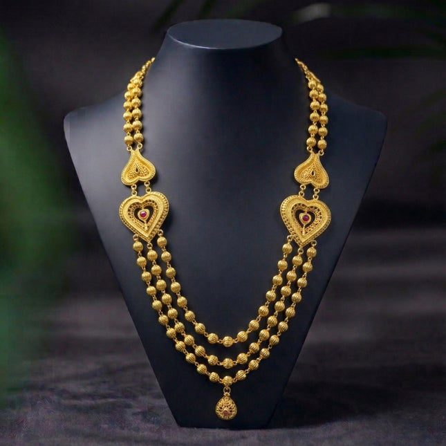 Gold necklace with heart-shaped pendants on a black mannequin against a dark background