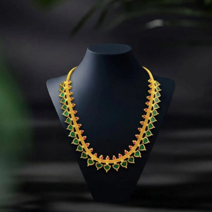 Gold and green necklace on a black mannequin against a dark background