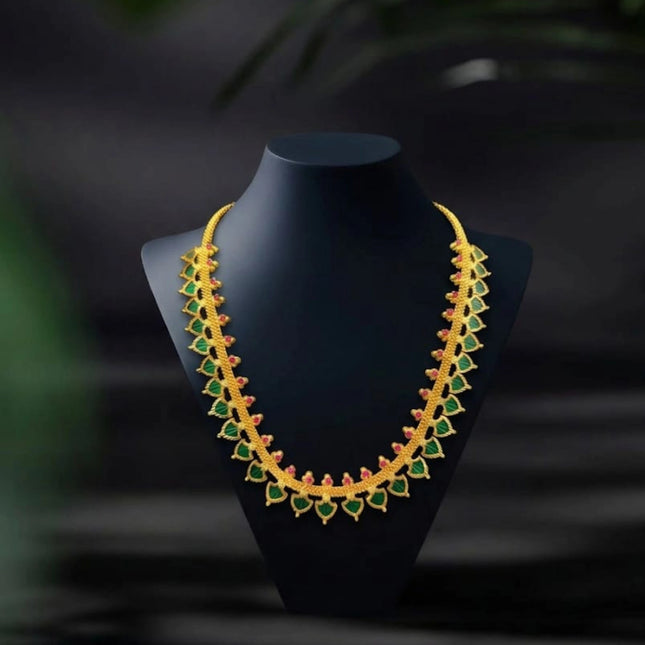 Gold and green necklace on a black mannequin against a dark background