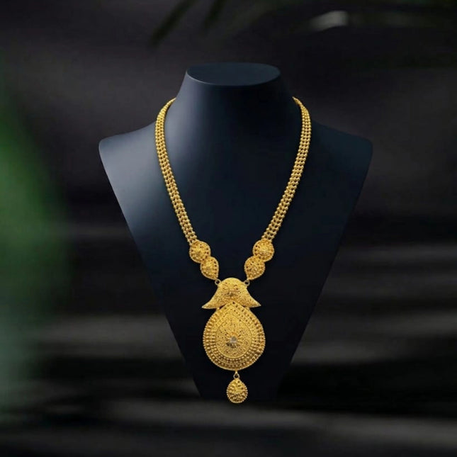 Gold necklace on a black mannequin bust against a dark background