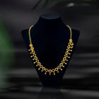 Gold necklace on a black mannequin bust with a dark background