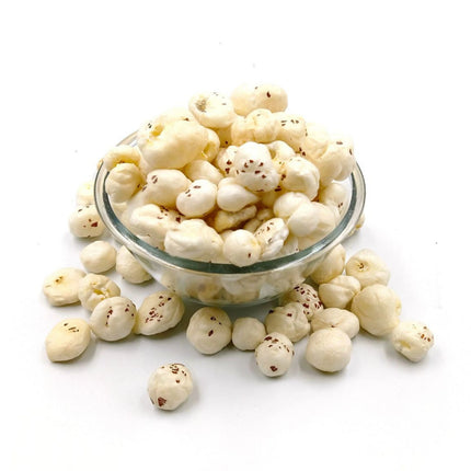 Glass bowl filled with white popcorn-like snacks on a white background