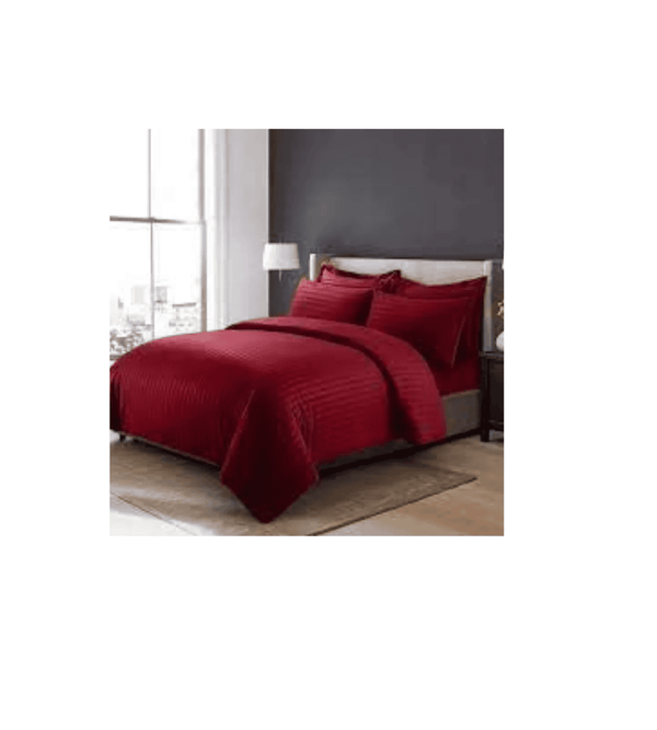 Red bedspread set on a bed in a room with a gray wall and window.