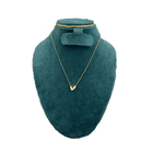 Gold necklace on a green velvet mannequin bust with a white background