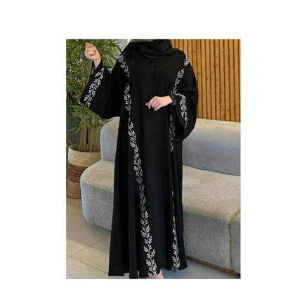 Black abaya with white embroidery worn by a person in a living room setting.