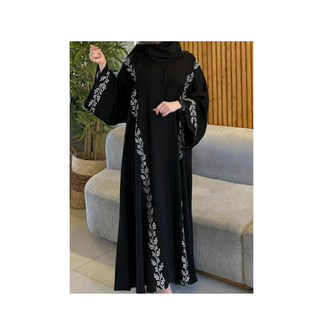 Black abaya with white embroidery worn by a person in a living room setting.