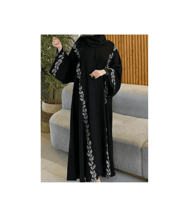 Black abaya with white embroidery worn by a person in a living room setting.